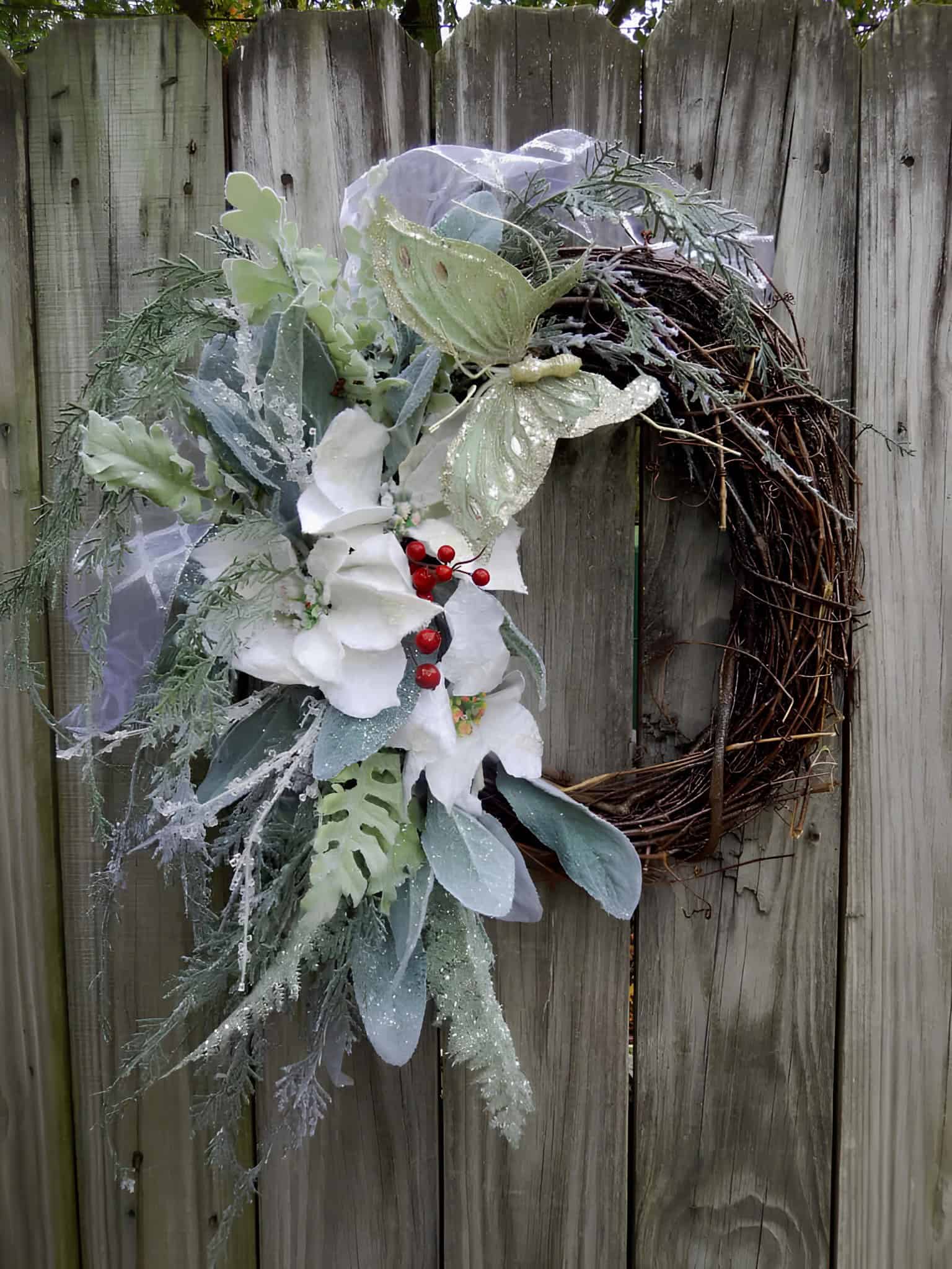 Wooden grapevine wreath with silver greenery, white poinsettias and a decorative butterfly