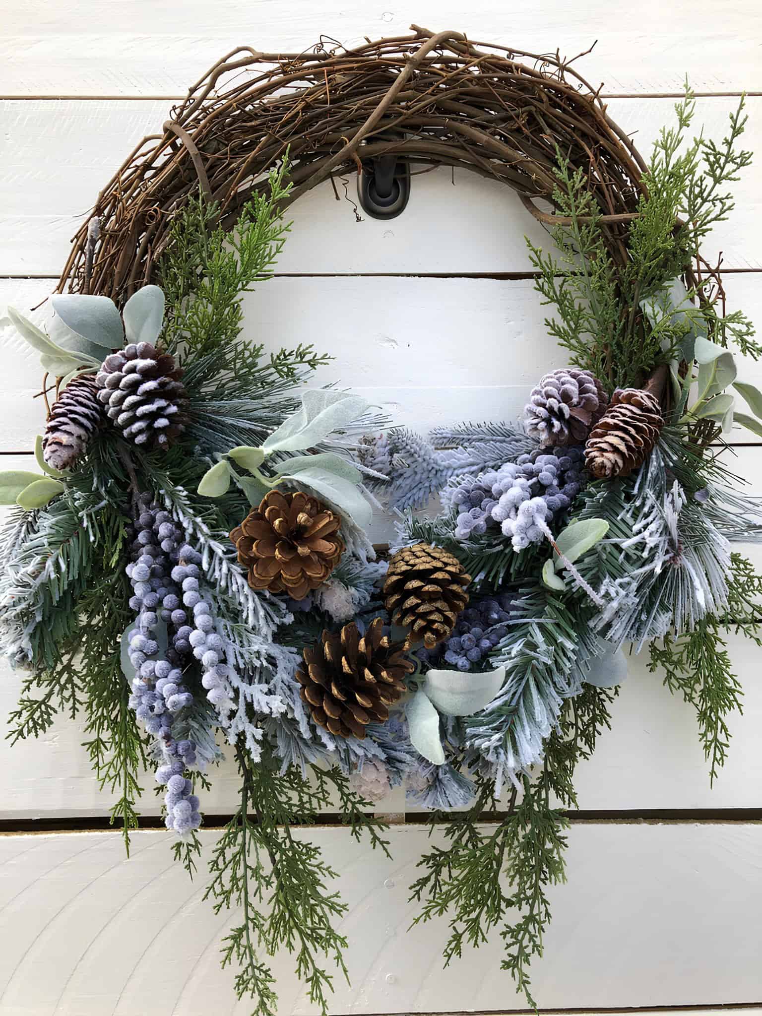 Frosted winter pine wreath with pinecones, eucalyptus, and greenery for holiday home decoration.