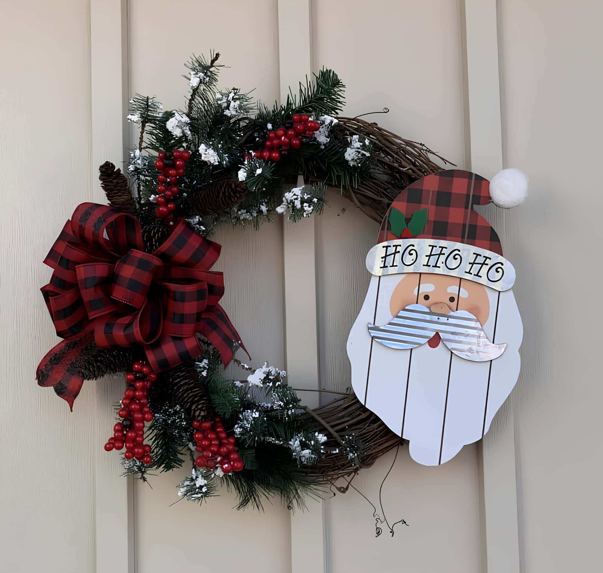 Festive Christmas wreath with pine branches, red berries, pinecones, and a large red plaid bow decorates a door for holiday celebration.