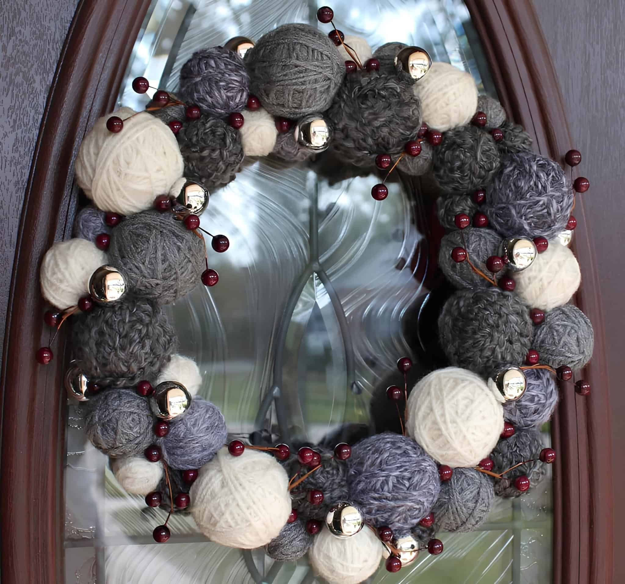 Rustic wreath made from yarn balls in neutral colors with red berries and bells