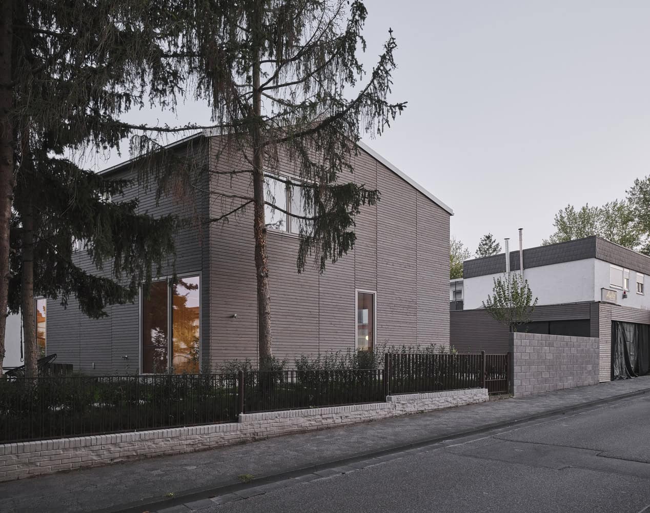 Contemporary modern house with natural wood siding, large windows, minimalist design, and a surrounding garden, exemplifying innovative residential architecture and sustainable building materials.