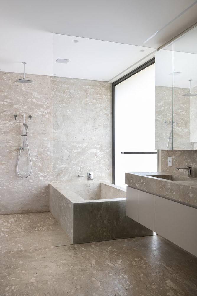 Bathroom interior with stone bathtub and shower at FE House by N2B Arquitetura
