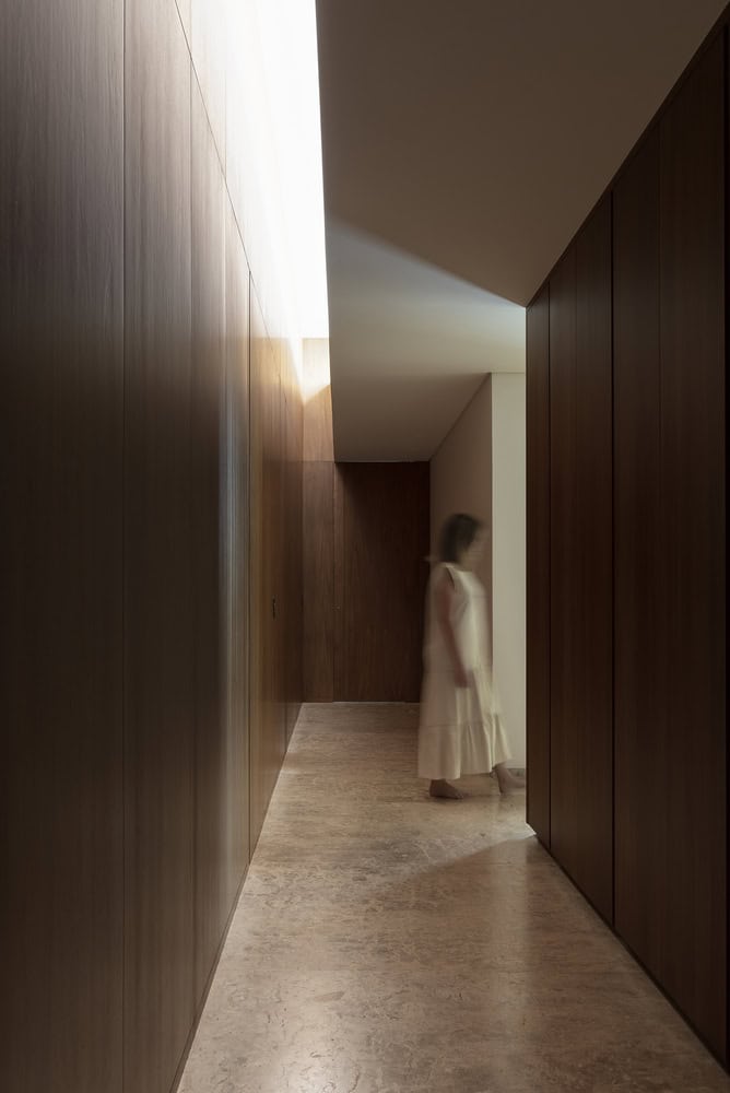 Soft-lit hallway with wooden wall panels inside FE House by N2B Arquitetura