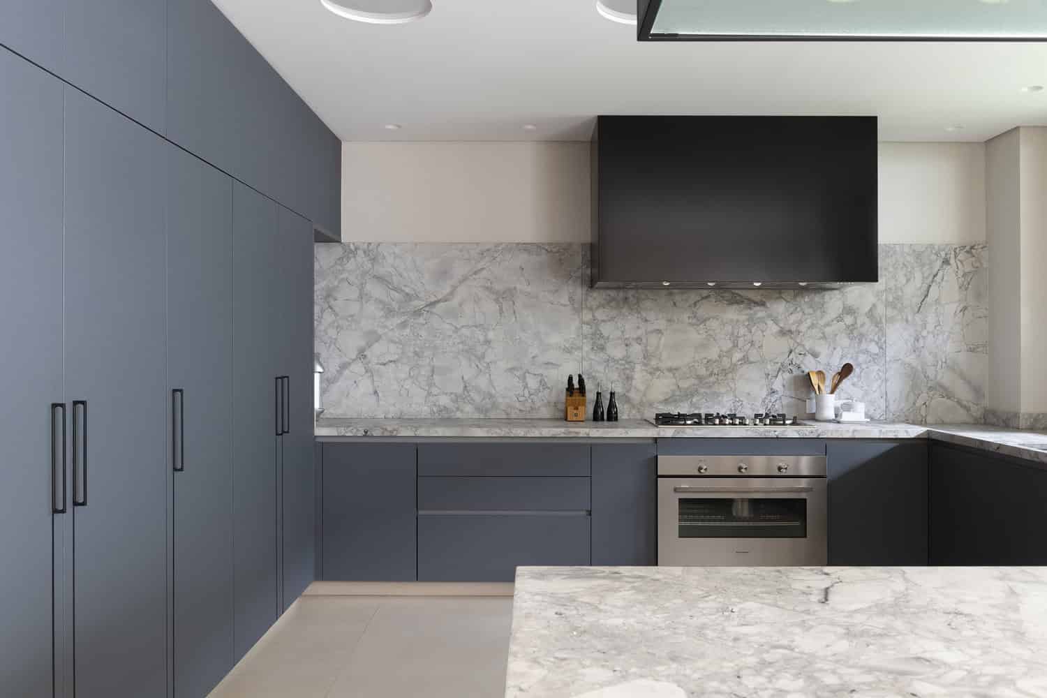Marble backsplash and modern cabinetry in FE House kitchen by N2B Arquitetura