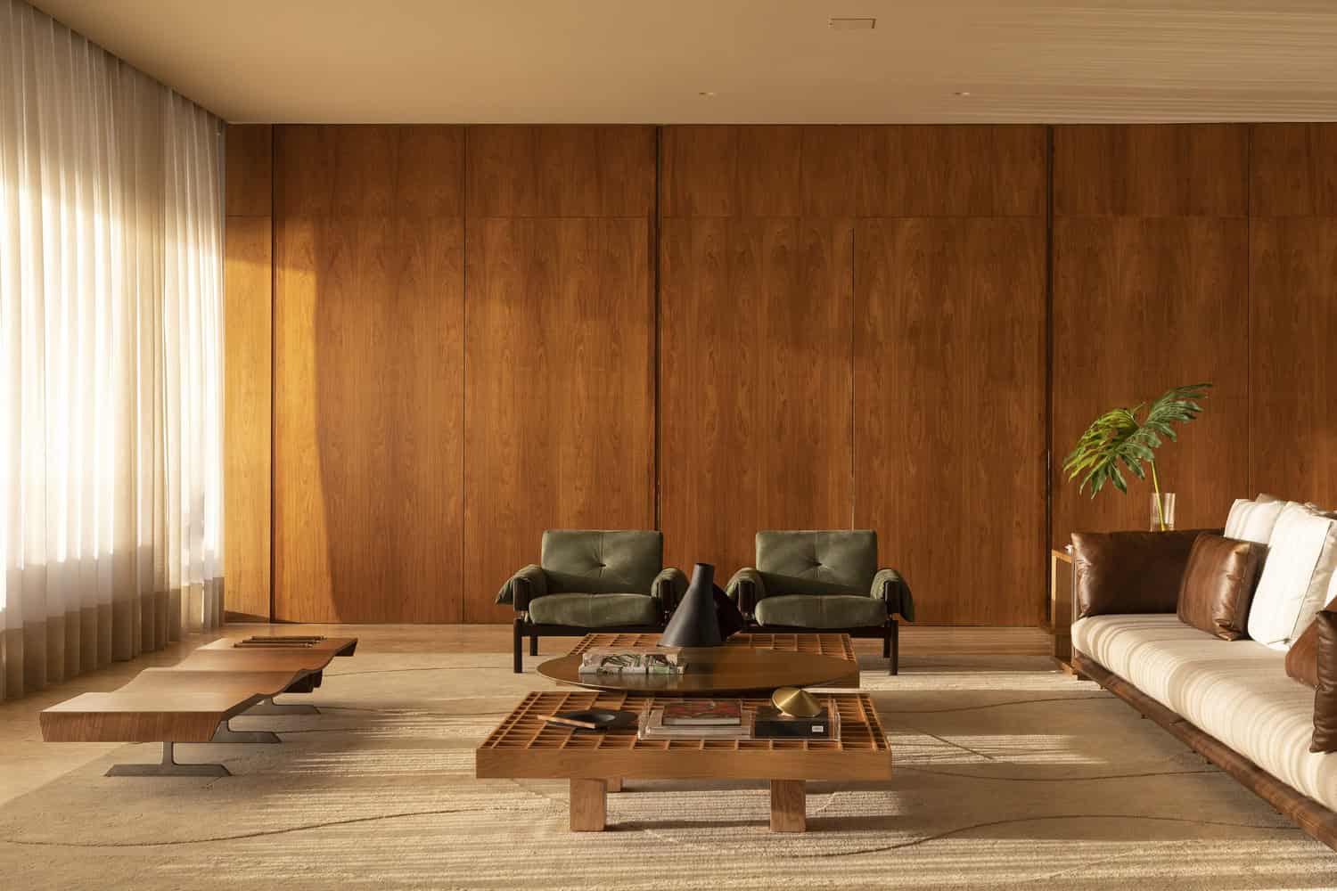 Living room seating with wood panel wall at FE House by N2B Arquitetura