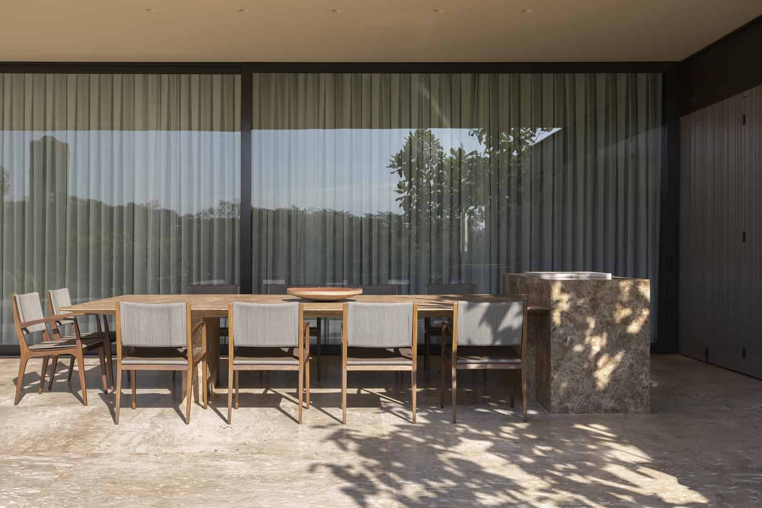 FE House by N2B Arquitetura outdoor dining terrace with long wooden table in Ribeirão Preto, Brazil