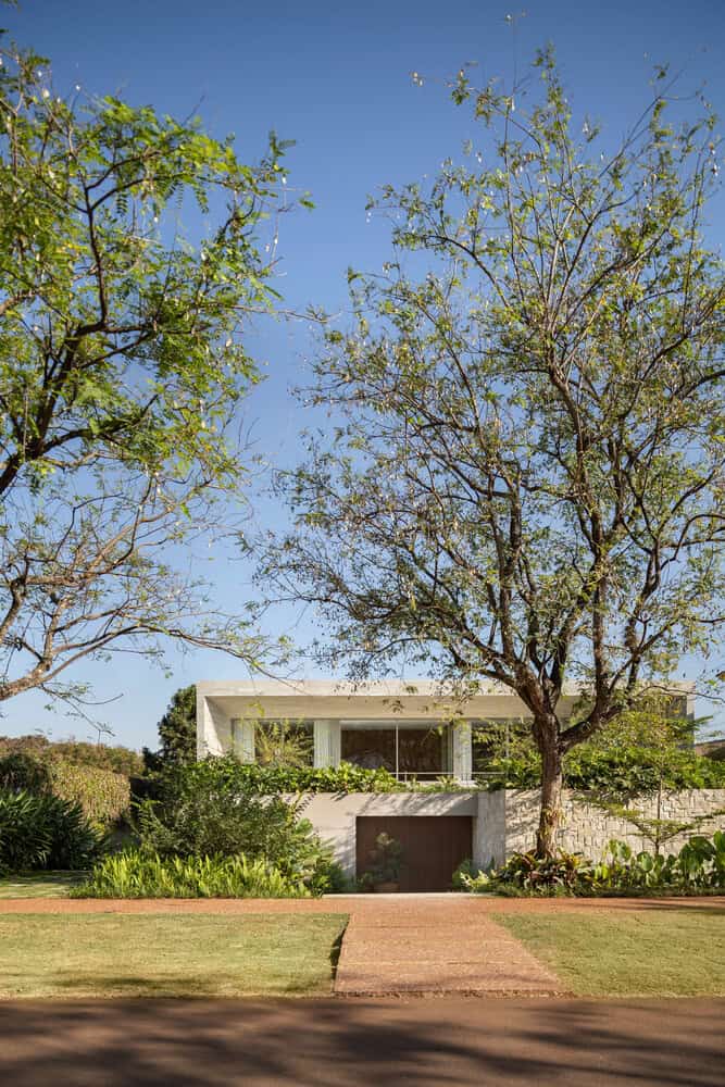 Street facade of House AL framed by trees by N2B Arquitetura in Vila do Golfe, Brazil