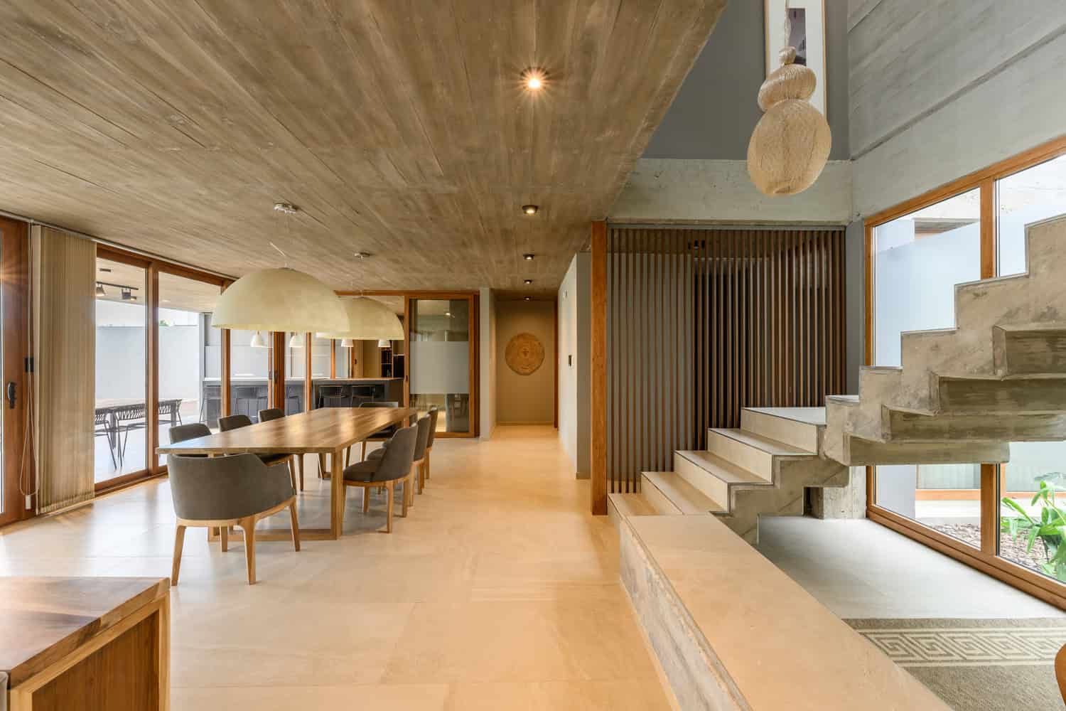 House G by Karlen + Clemente — exposed concrete staircase by dining area, Río Tercero