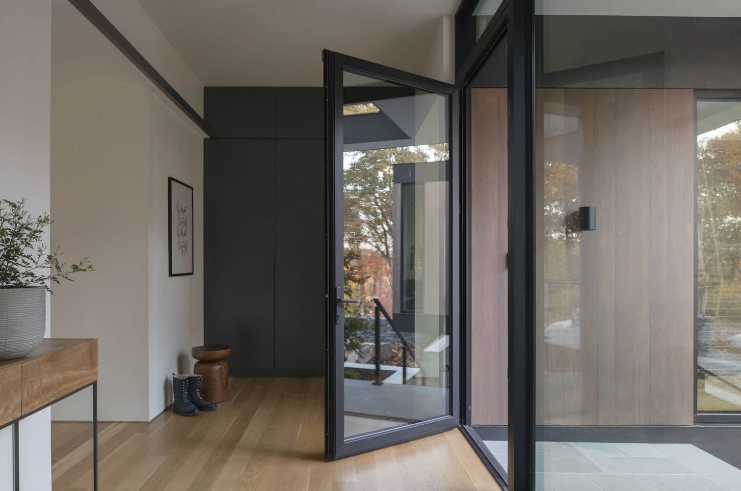 House in the Woods by Tom Lontine Architect, foyer with large pivot door and forest view in Connecticut