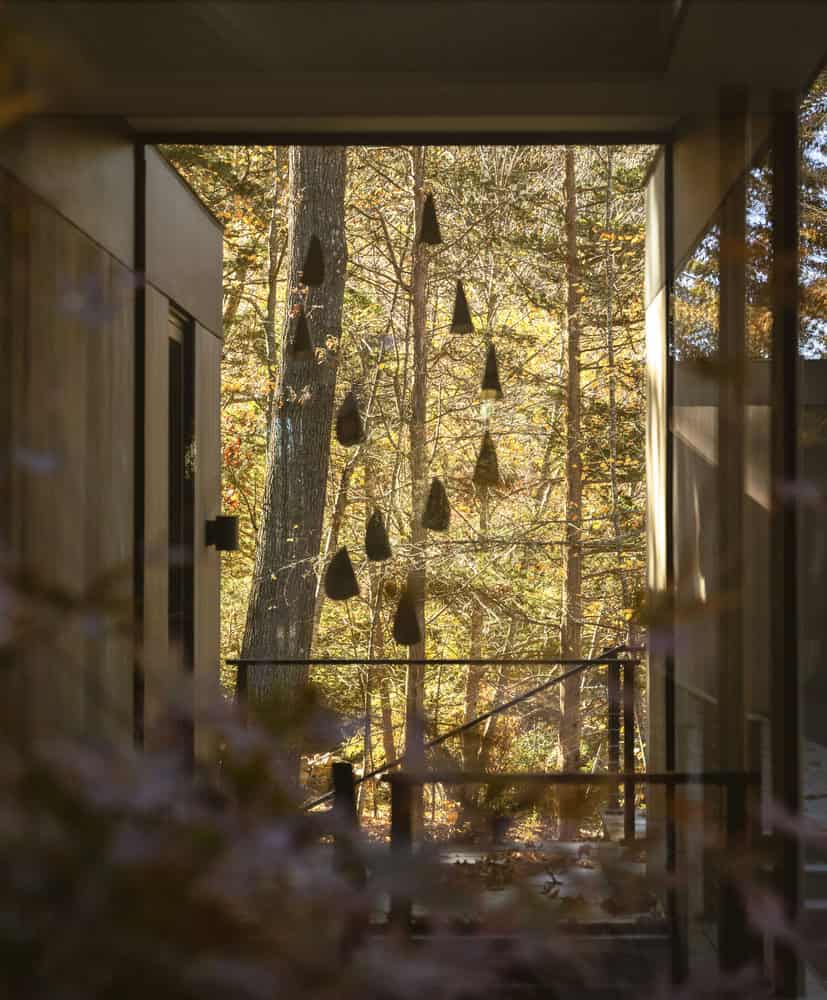 House in the Woods by Tom Lontine Architect, hallway with hanging sculpture and forest view in Connecticut