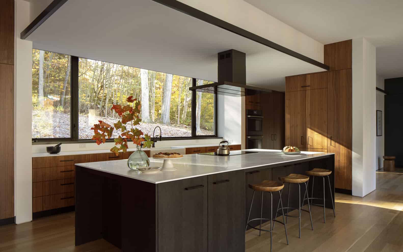 House in the Woods by Tom Lontine Architect, kitchen island with long window to woodland slope in Connecticut