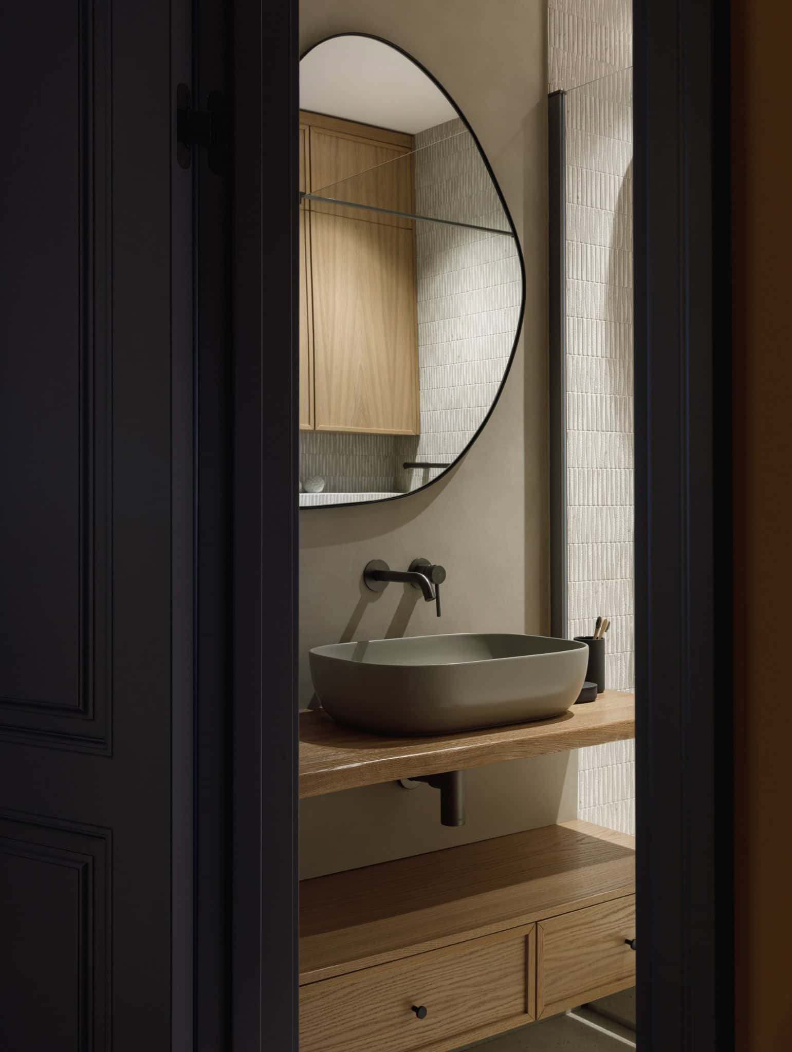 Organic mirror and vanity seen from doorway in Lesoparkovy Apartment bathroom by STARIKOVA.ARCHITECTS