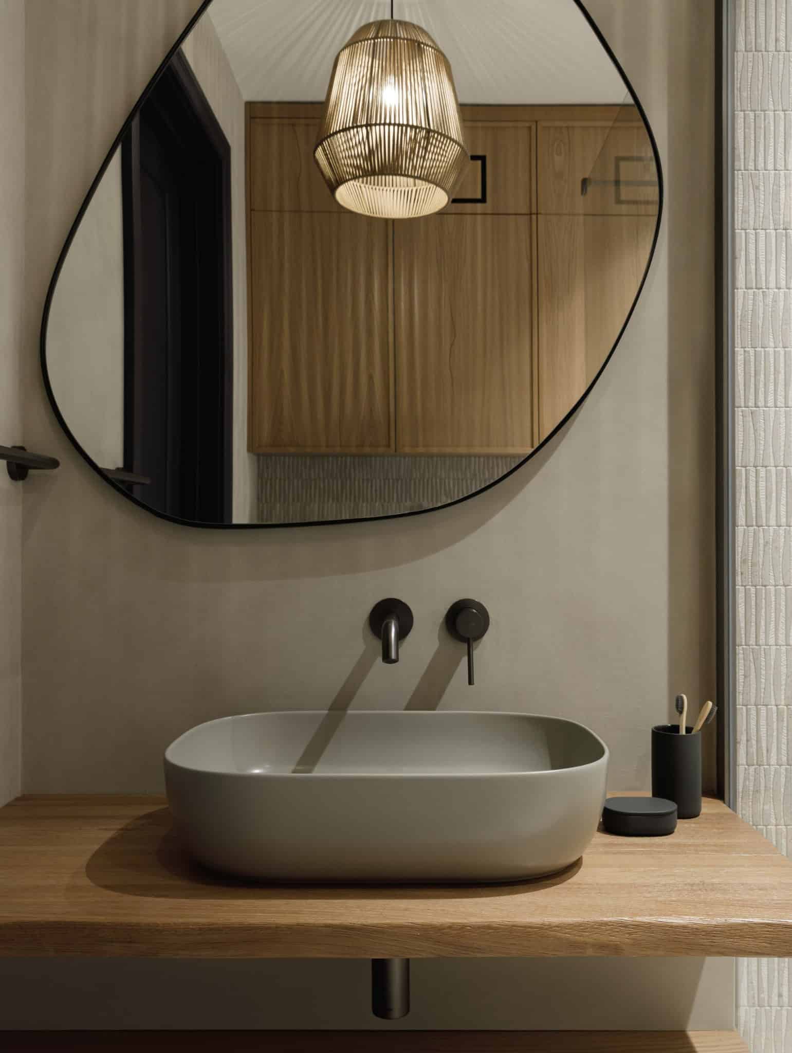 Sculptural organic mirror above vanity in Lesoparkovy Apartment bathroom by STARIKOVA.ARCHITECTS