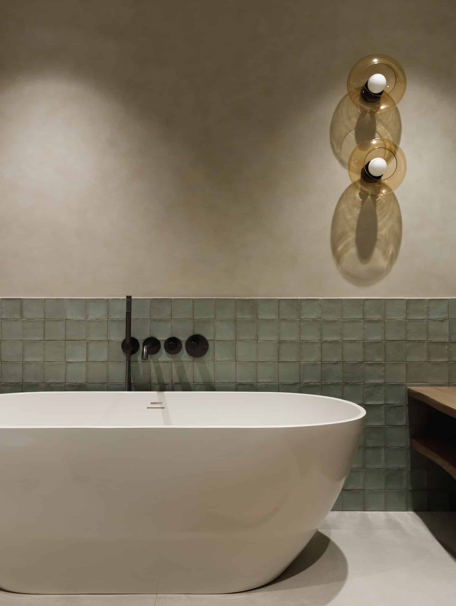 Modern bathroom with freestanding tub and green tile wall in Lesoparkovy Apartment by STARIKOVA.ARCHITECTS in Chelyabinsk