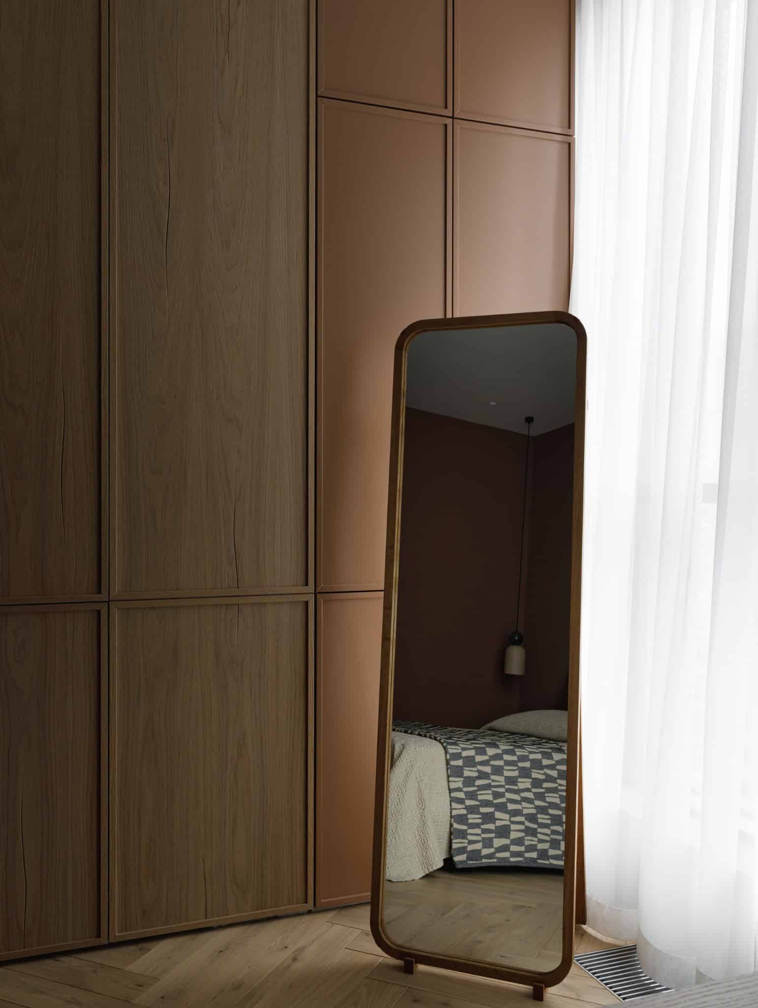 Floor mirror reflecting bedroom and wardrobe in Lesoparkovy Apartment by STARIKOVA.ARCHITECTS