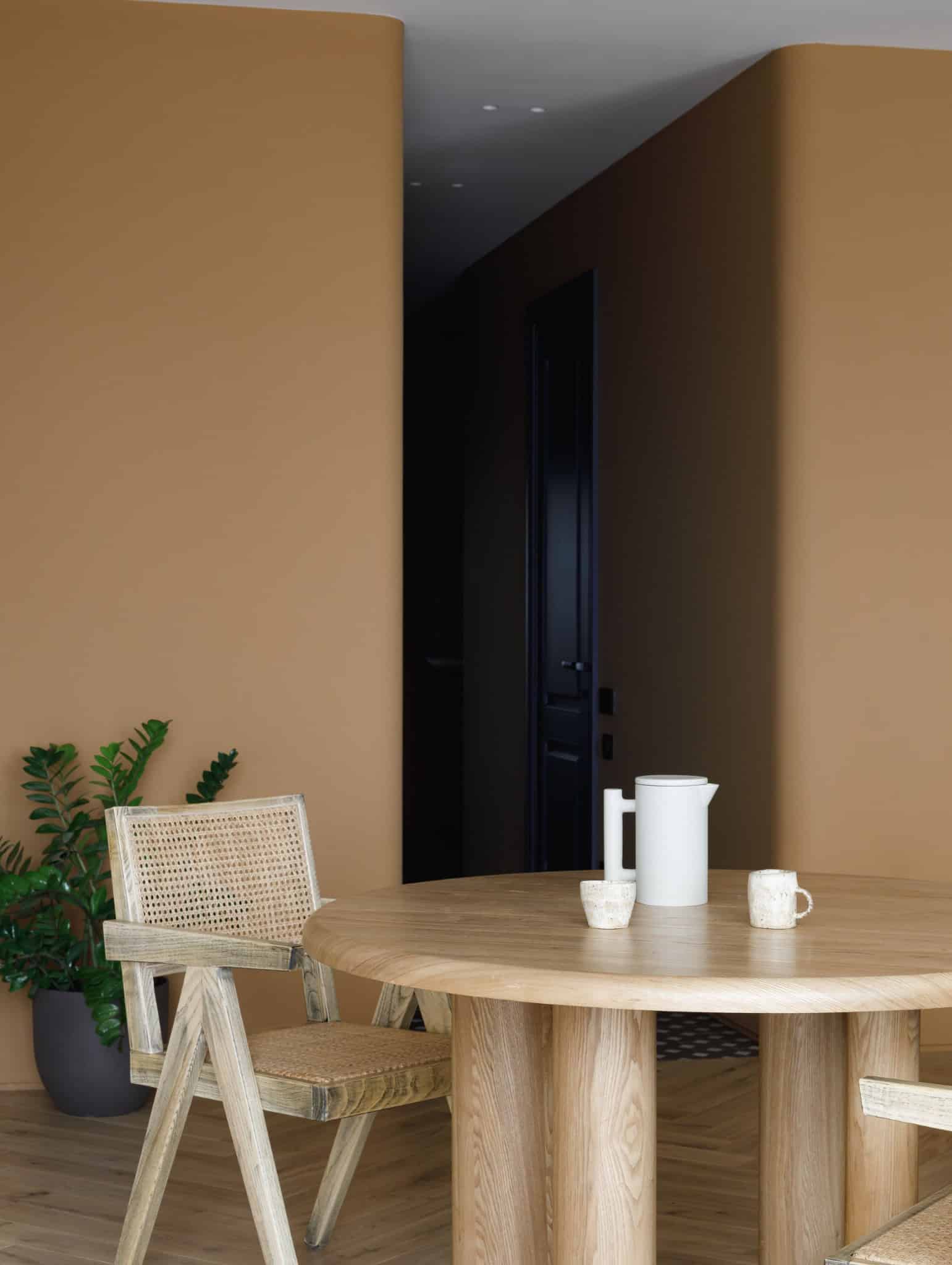 Lesoparkovy Apartment by STARIKOVA.ARCHITECTS round wooden dining table with woven chairs in Chelyabinsk, Russia