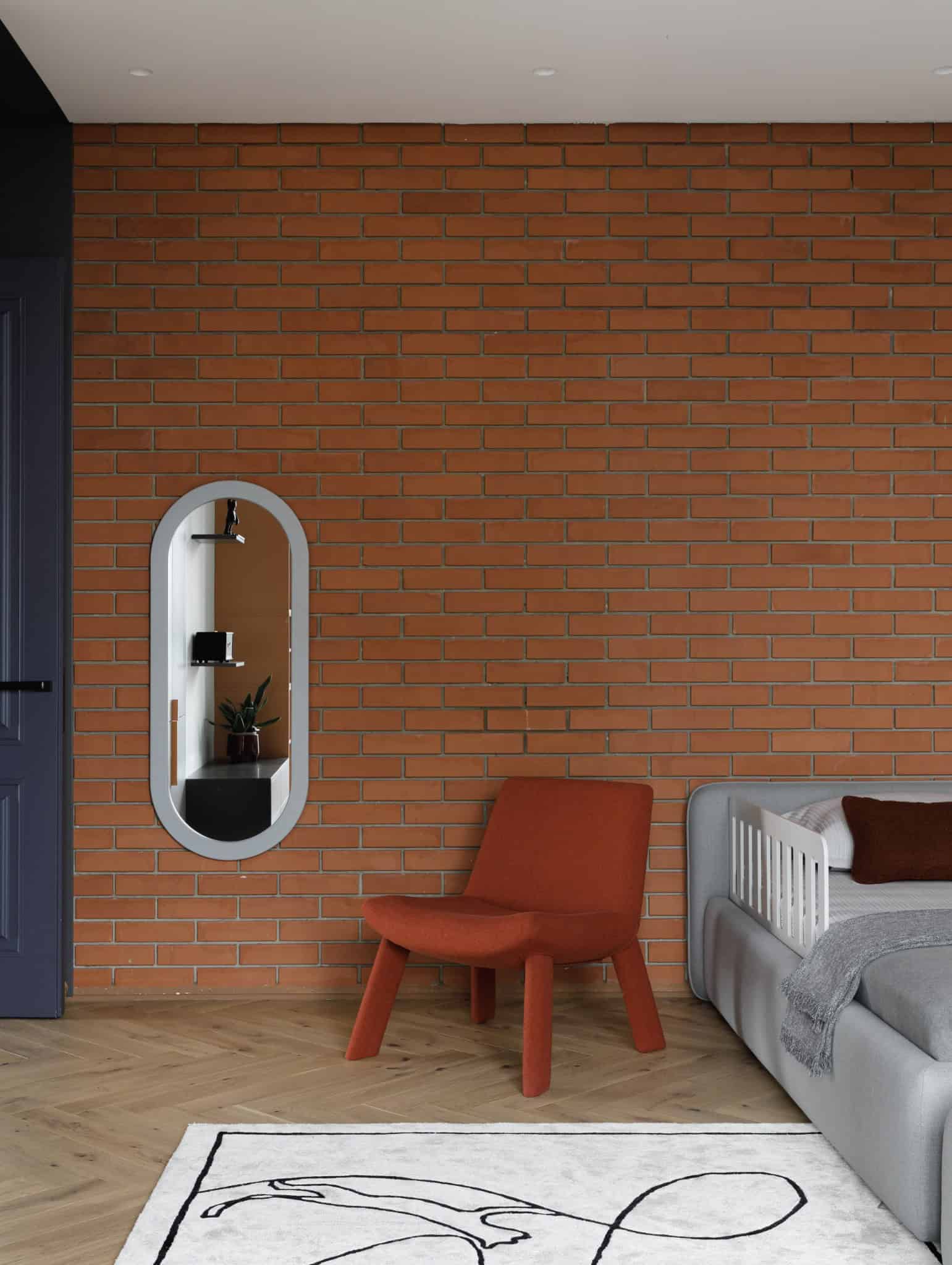 Kids room orange chair and brick wall in Lesoparkovy Apartment by STARIKOVA.ARCHITECTS