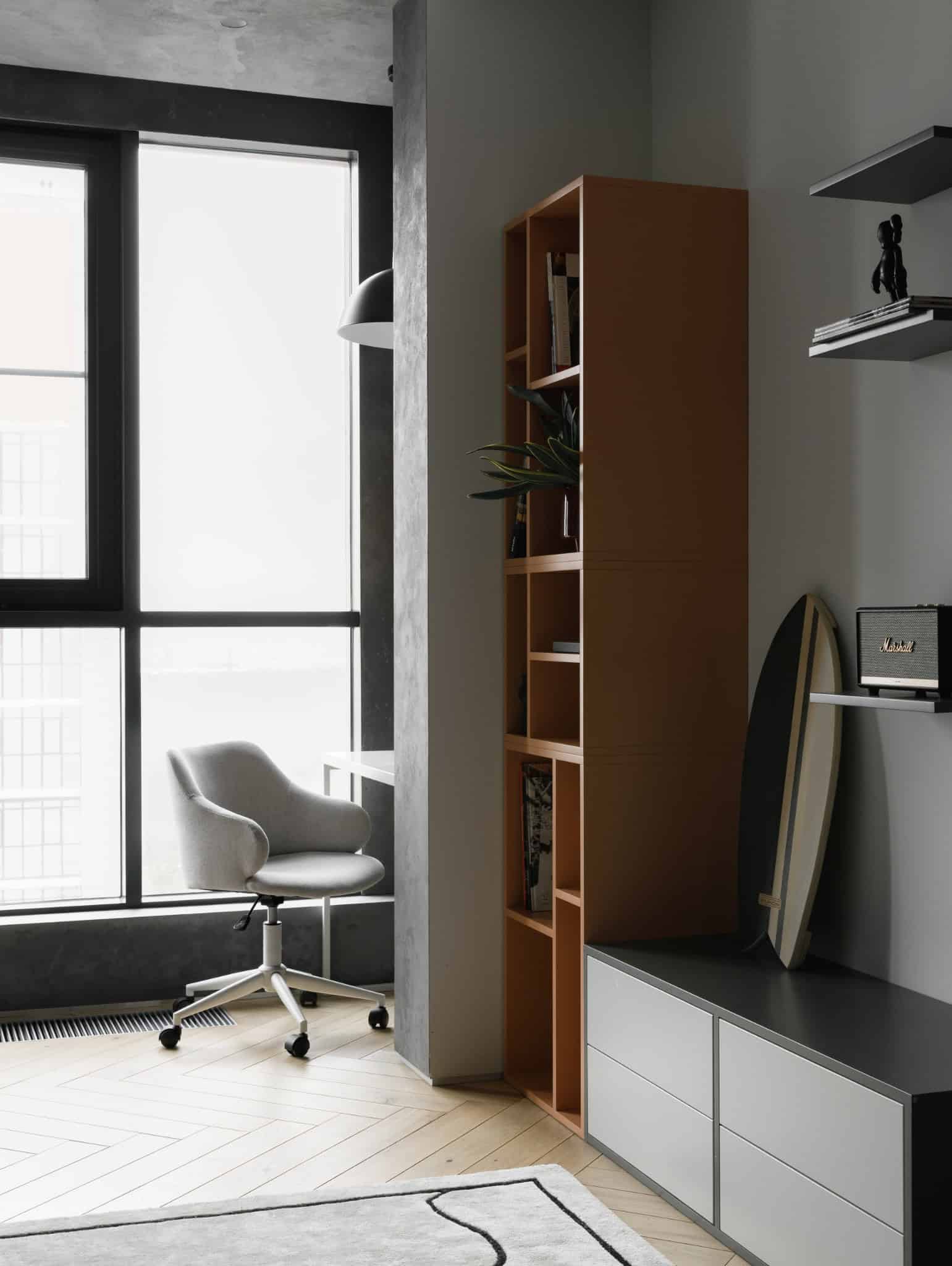 Study area with grey chair and tall bookshelf in Lesoparkovy Apartment by STARIKOVA.ARCHITECTS
