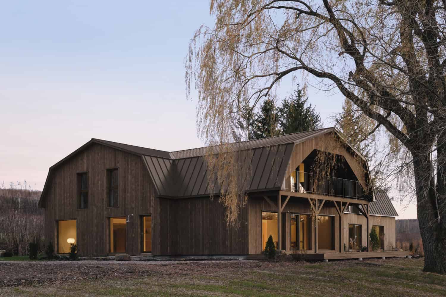 Maison Melba by Atelier L’Abri barn-inspired front facade at dusk in Frelighsburg, Quebec
