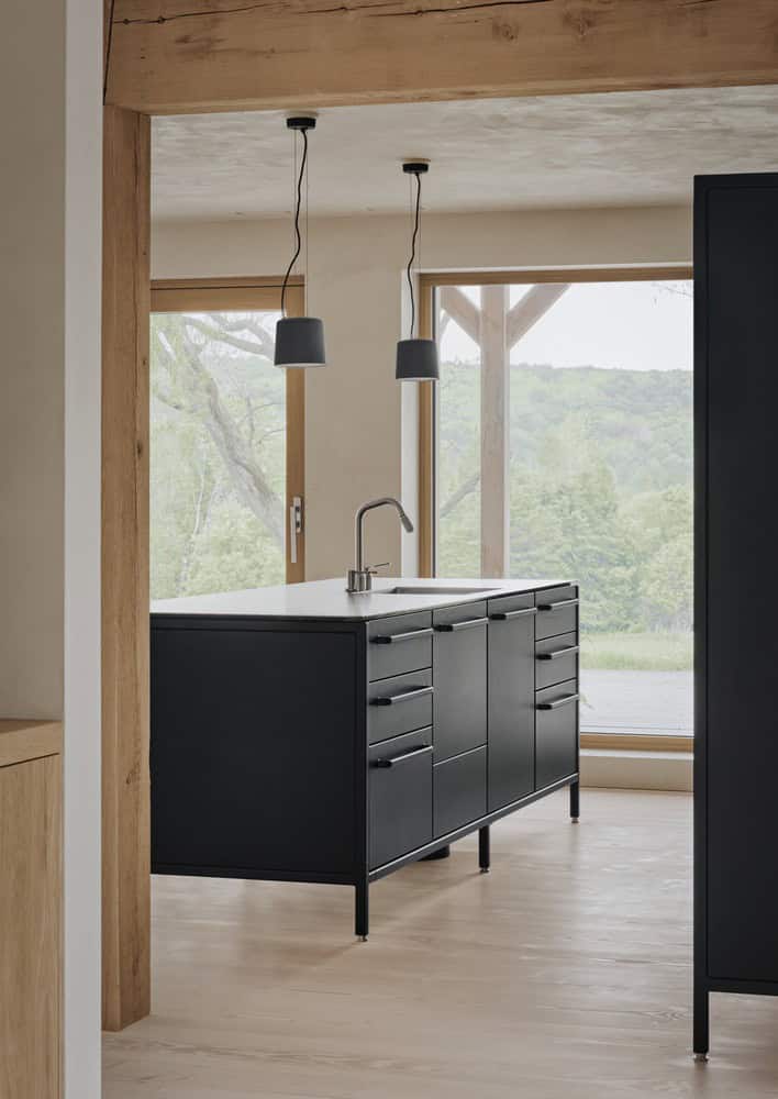 Maison Melba kitchen by Atelier L’Abri with black island and large windows to landscape in Frelighsburg, Quebec