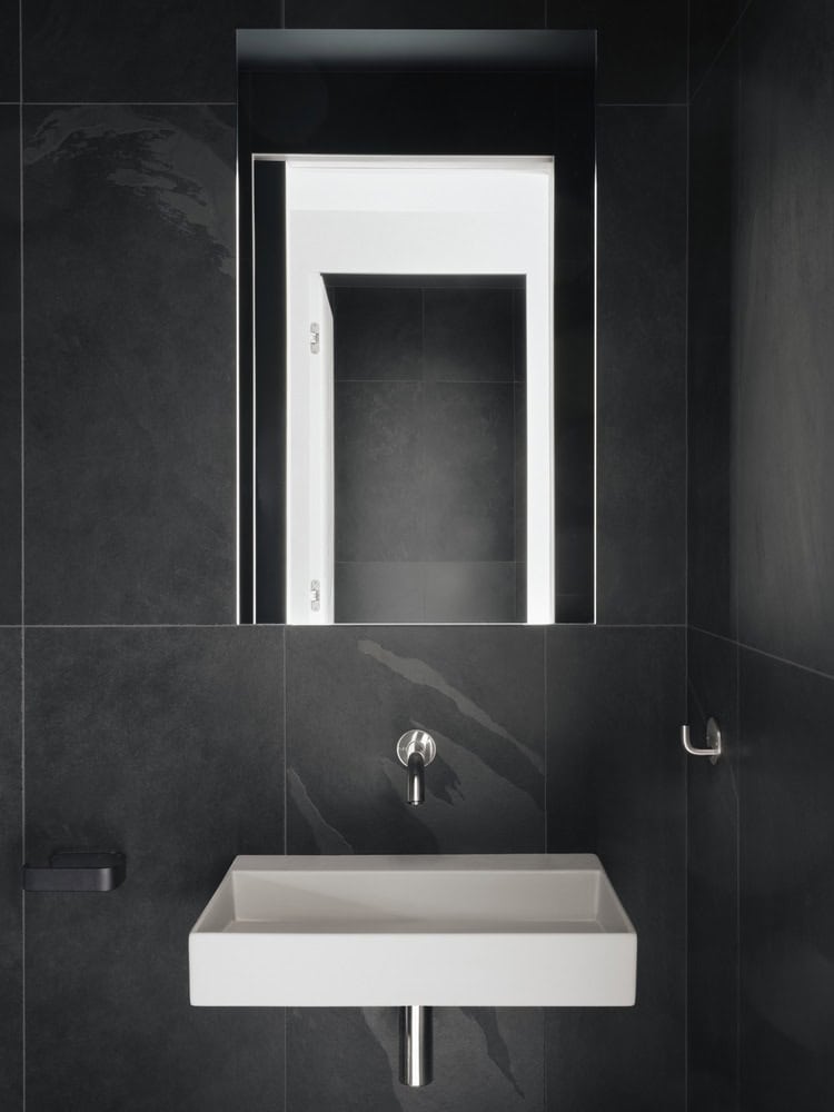 Maison Melba bathroom by Atelier L’Abri with black tiles and a minimalist white sink in Frelighsburg Quebec
