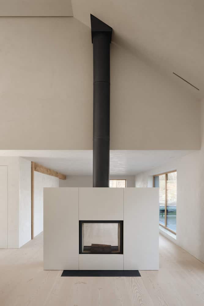 Maison Melba interior by Atelier L’Abri with central fireplace volume and black flue in Frelighsburg, Quebec