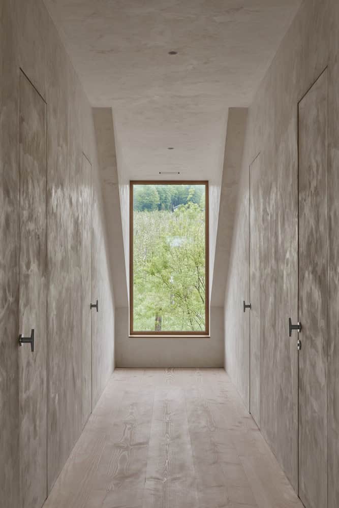 Maison Melba corridor by Atelier L’Abri with skylit ceiling and framed forest view in Frelighsburg, Quebec
