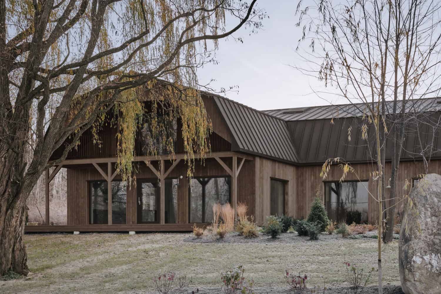Close view of Maison Melba by Atelier L’Abri showing covered porch and garden planting in Frelighsburg, Quebec