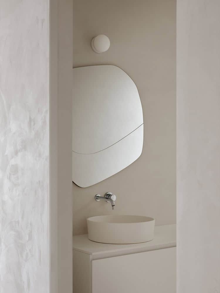 Maison Melba powder room by Atelier L’Abri with organic-shaped mirror and round basin in Frelighsburg, Quebec