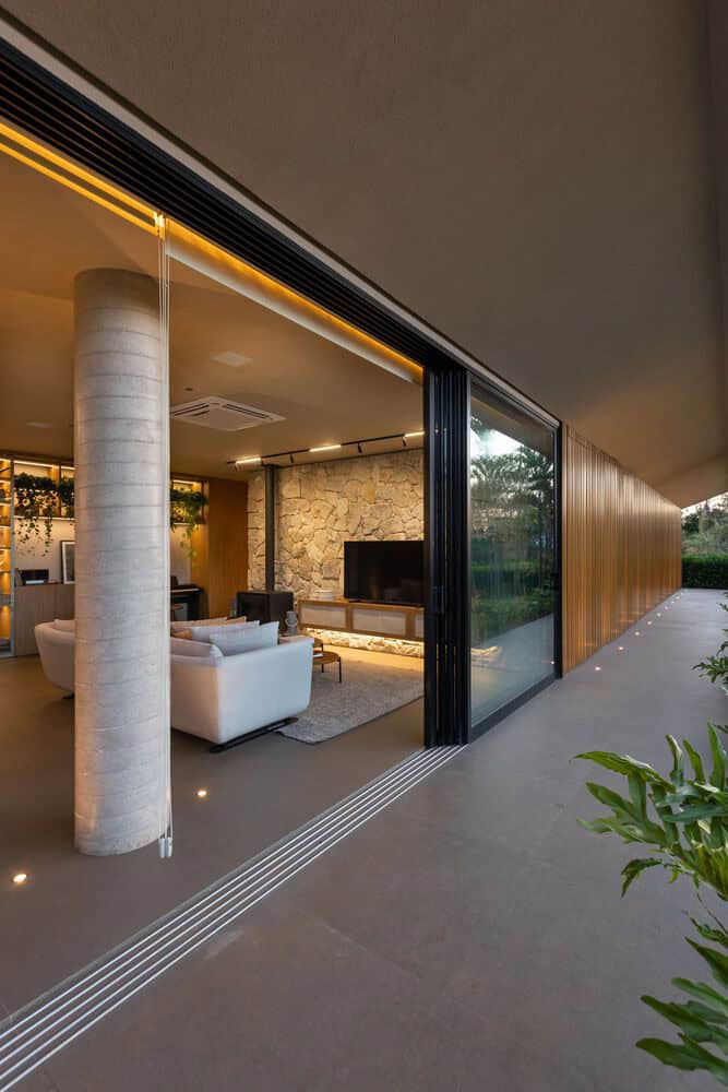 MCZ House Living Room Stone Wall by NIU Arquitetura e Construção MCZ House by NIU Arquitetura e Construção, living room with stone wall and sliding glass in Cristais Paulista, São Paulo, Brazil