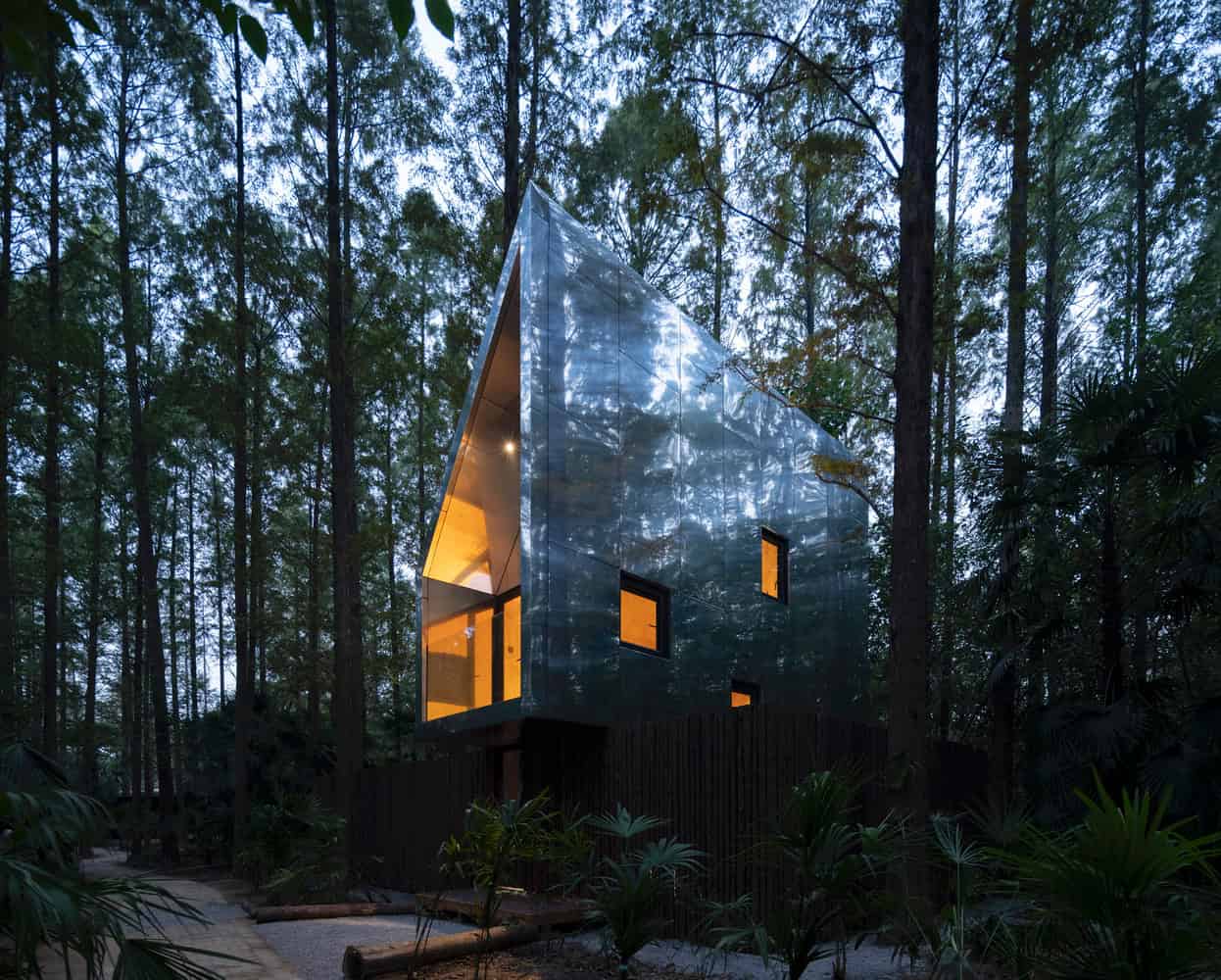 Merryda Wiki World-Secret Camp Metal Treehouse Elevated Forest Dusk by Wiki World + Advanced Architecture Lab Elevated metal-clad treehouse at Merryda Wiki World-Secret Camp in China at dusk