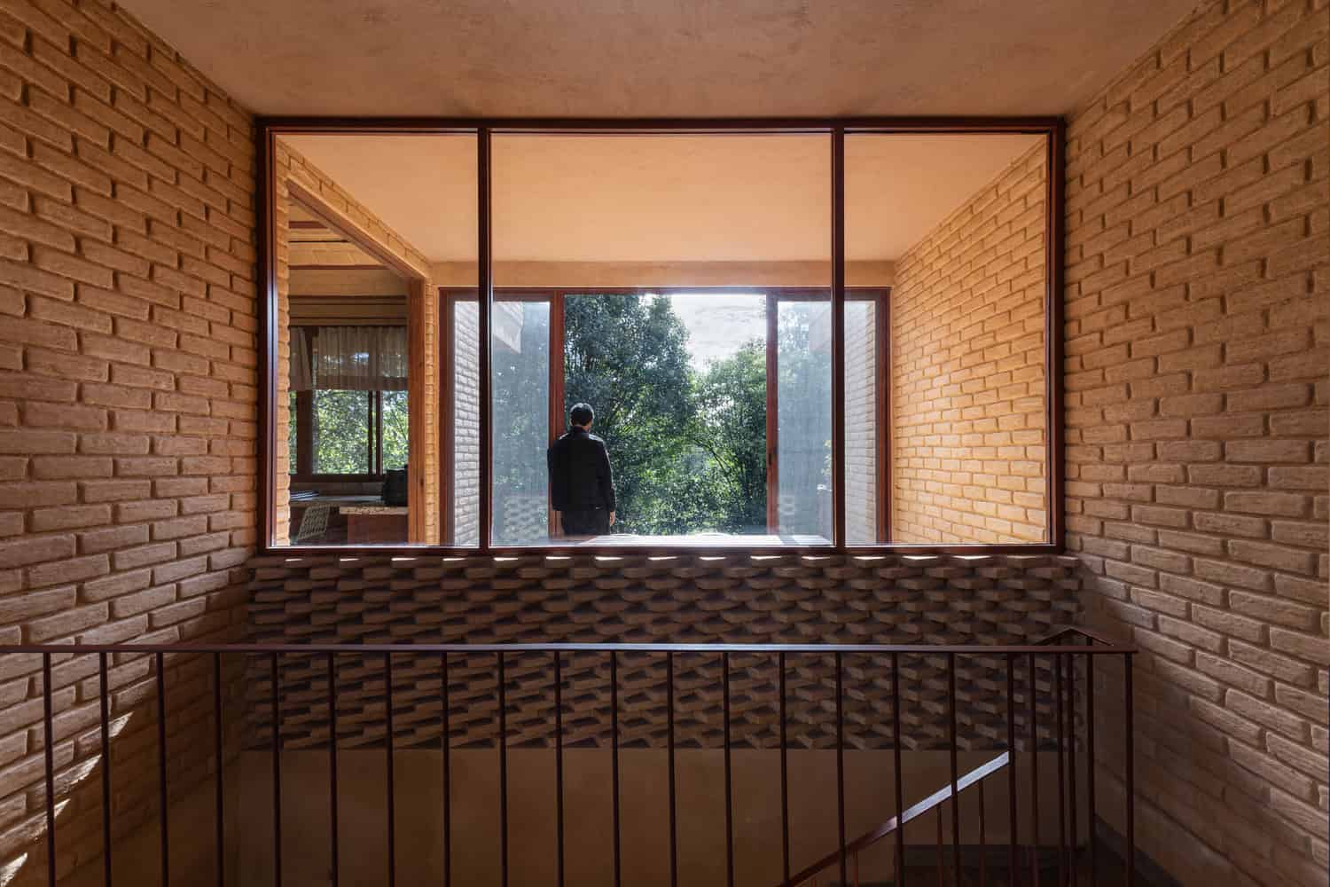 Brick-lined landing in The Sierra House by Valdez Arquitectos with a large window framing the surrounding forest in Chiapas, Mexico