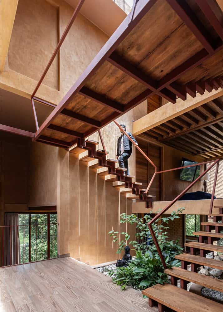 Floating timber staircase above zen garden in the central atrium of The Sierra House by Valdez Arquitectos in Chiapas, Mexico