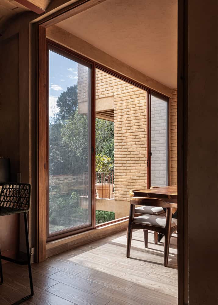 Corner breakfast nook in The Sierra House by Valdez Arquitectos with sliding glass doors opening to a brick balcony in Chiapas, Mexico