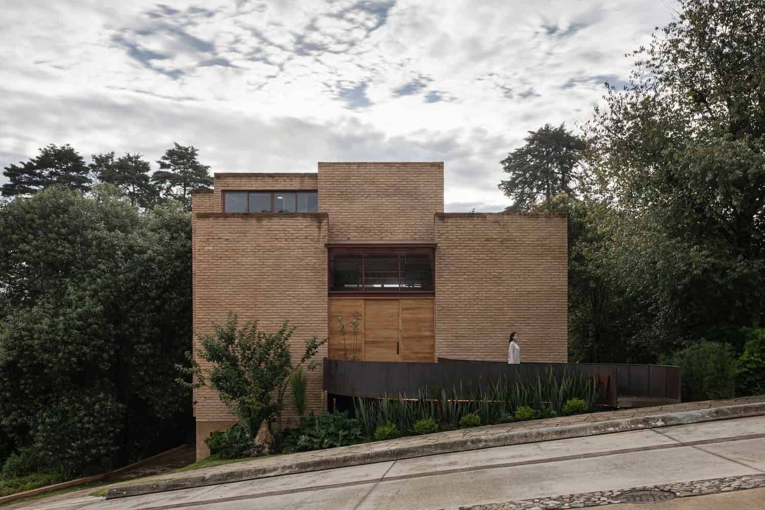 Front brick volume of The Sierra House by Valdez Arquitectos facing the sloping street in Chiapas, Mexico