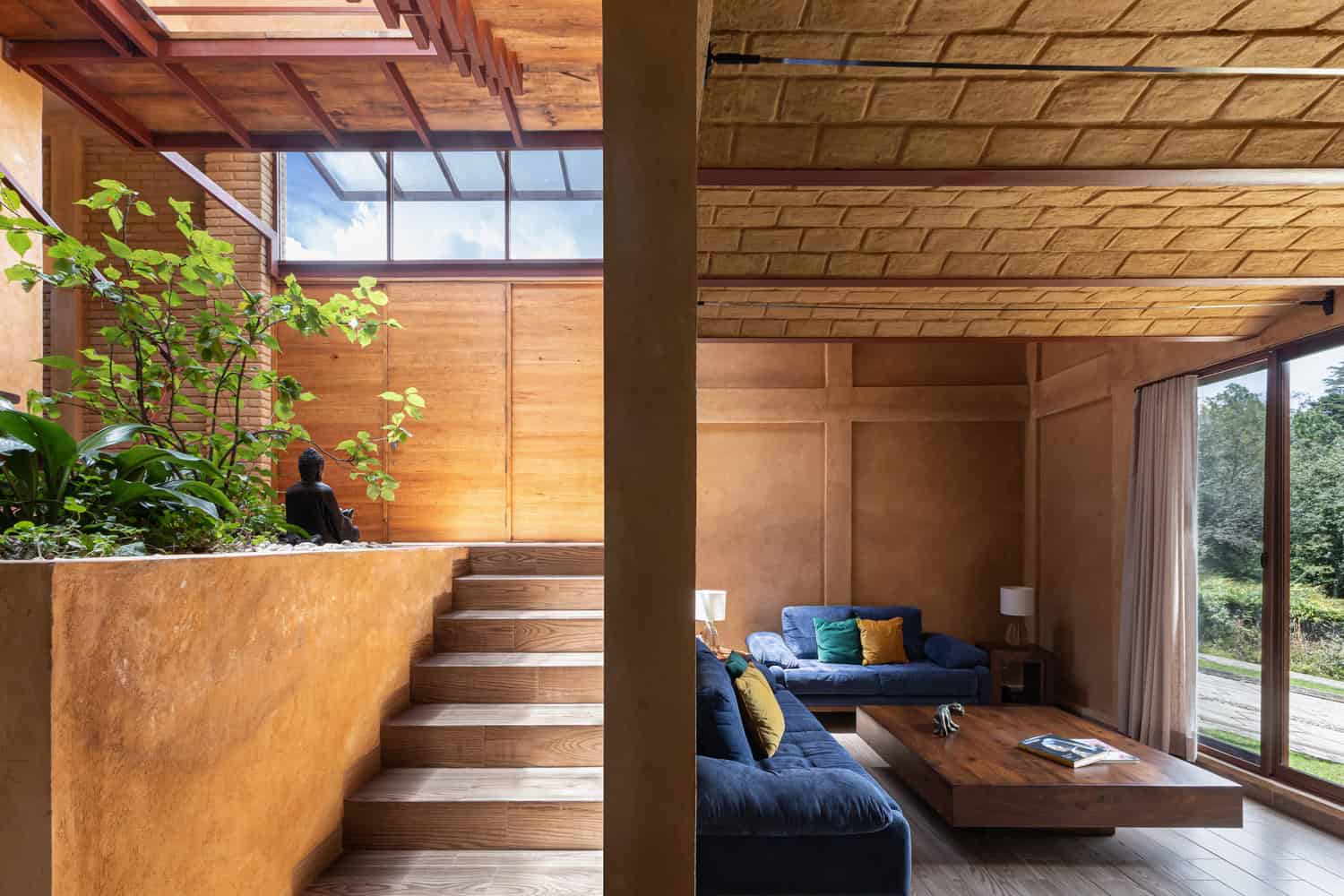 Warm living room of The Sierra House by Valdez Arquitectos with blue sofas, timber finishes and garden views in Chiapas, Mexico