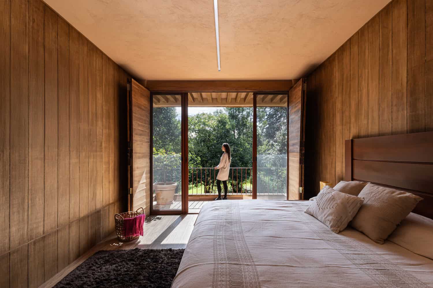 Master bedroom of The Sierra House by Valdez Arquitectos opening to a balcony with lush garden views in Chiapas, Mexico