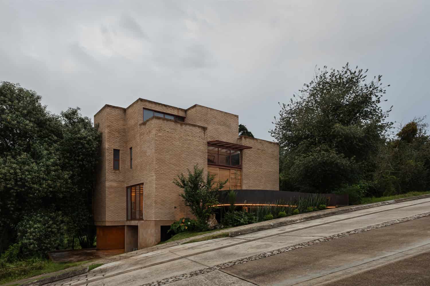 Street-facing brick facade of The Sierra House by Valdez Arquitectos on a steep slope in Chiapas, Mexico