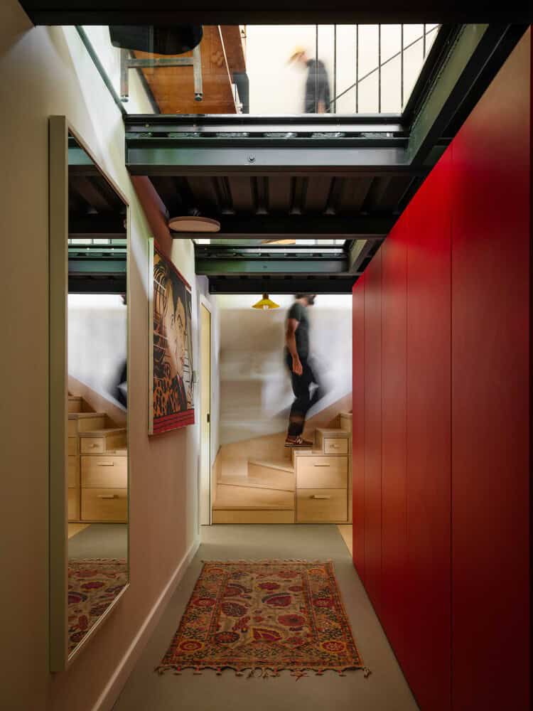 Bright modern interior with staircase and colorful artwork, featuring skylights and sleek red wall accents, exemplifies contemporary architecture and innovative design for stylish living spaces.