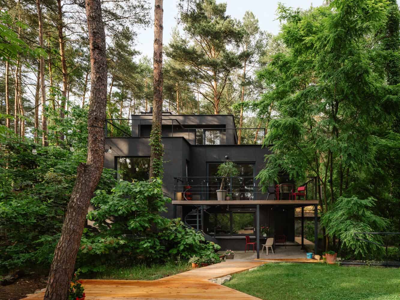 Daytime rear facade of Skubianka House by SZCZ Jakub Szczesny framed by forest trees in Skubianka