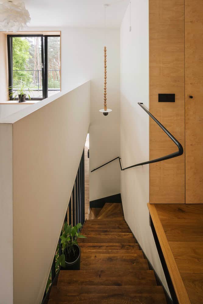 Aesthetic staircase with wooden steps and modern black railing in minimalist home interior, natural lighting from window, stylish decor, ideal for modern architecture art designs.