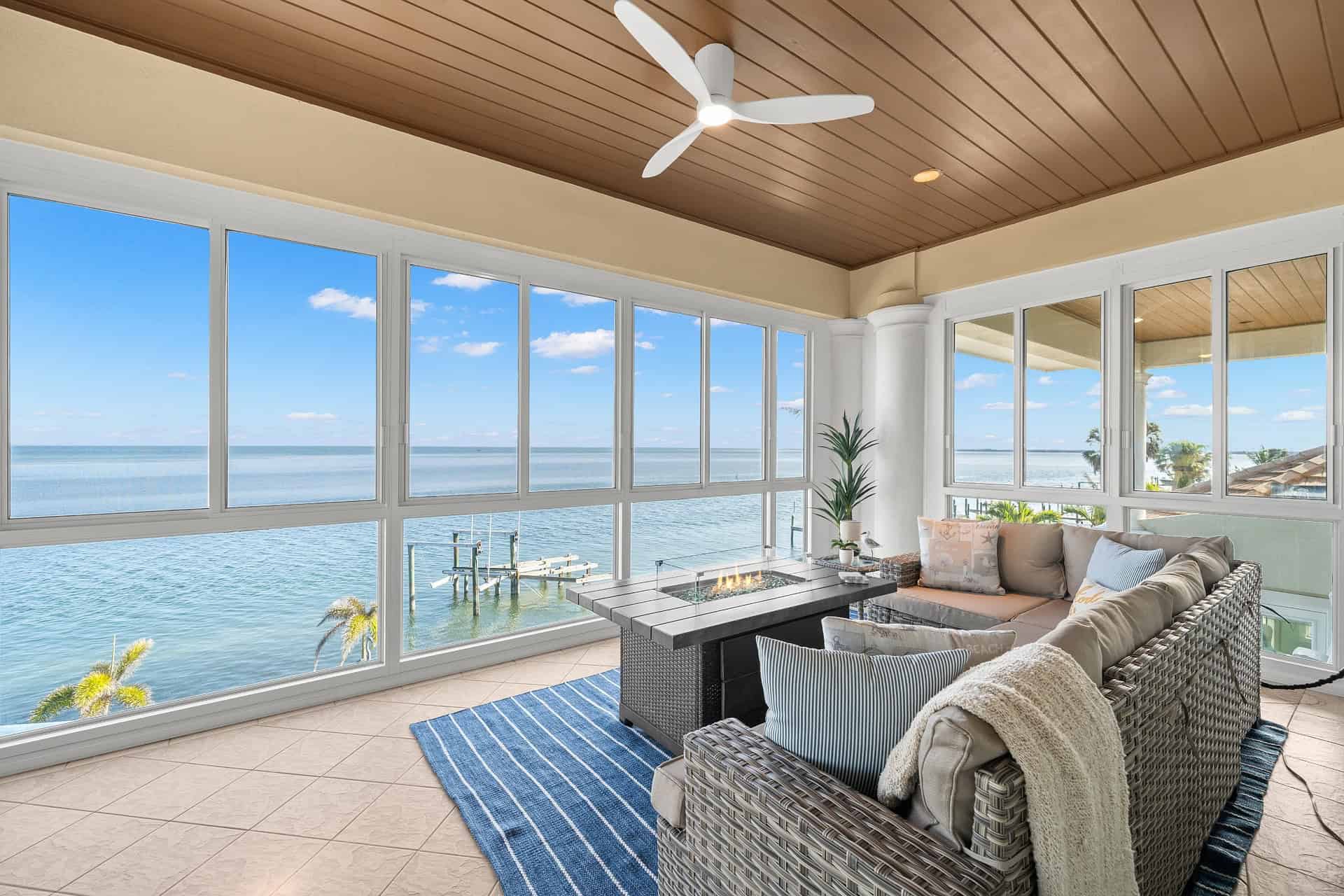 Breathtaking ocean view living room with large windows, modern ceiling fan, cozy sofa, and nautical decor, perfect for coastal home design and outdoor living inspiration.