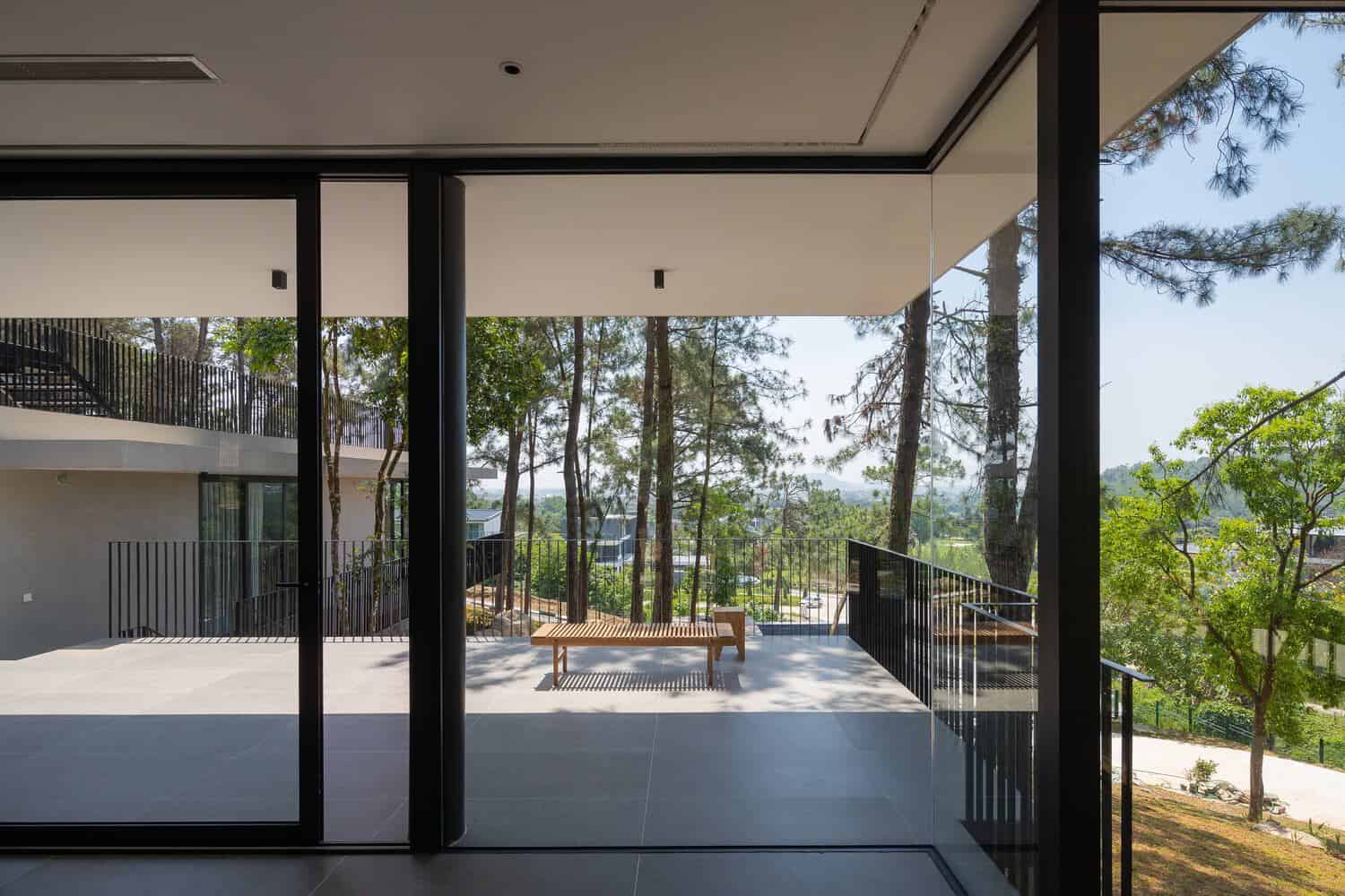 Tam Dao Retreat House by Idee architects covered terrace with bench overlooking forest in Tam Dao, Vietnam