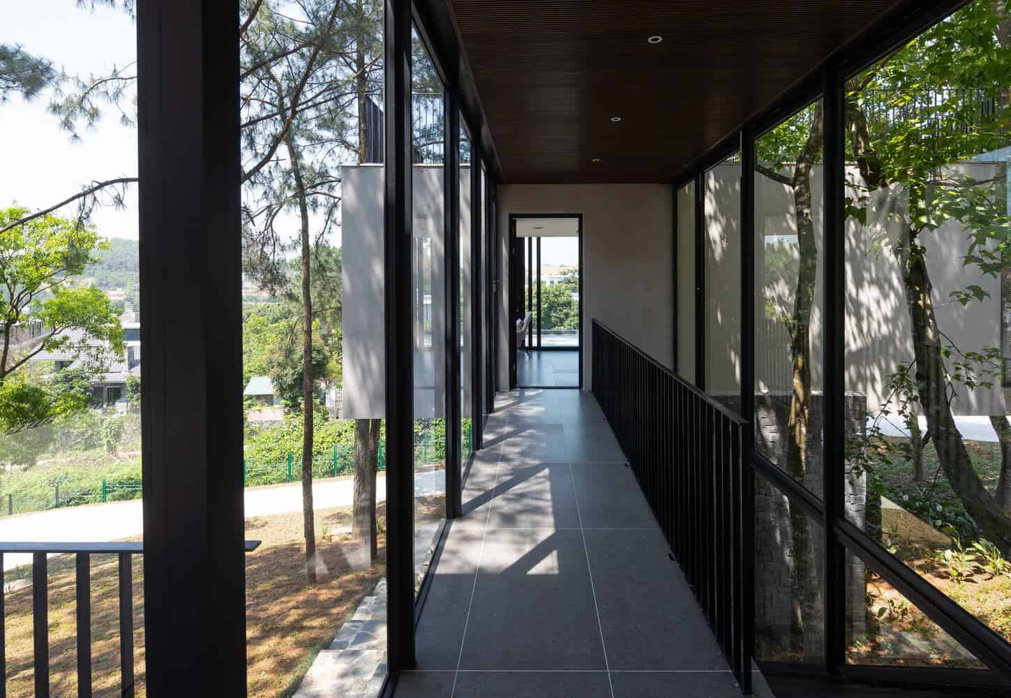 Tam Dao Retreat House by Idee architects glass corridor overlooking forest in Tam Dao, Vietnam