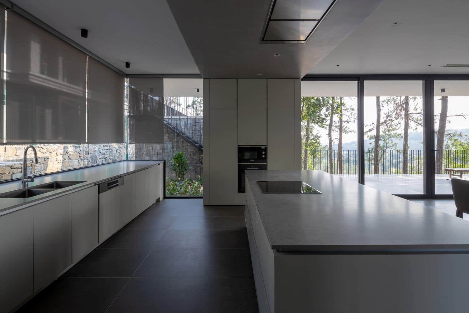 Tam Dao Retreat House by Idee architects minimalist kitchen with long counter and forest views in Tam Dao, Vietnam