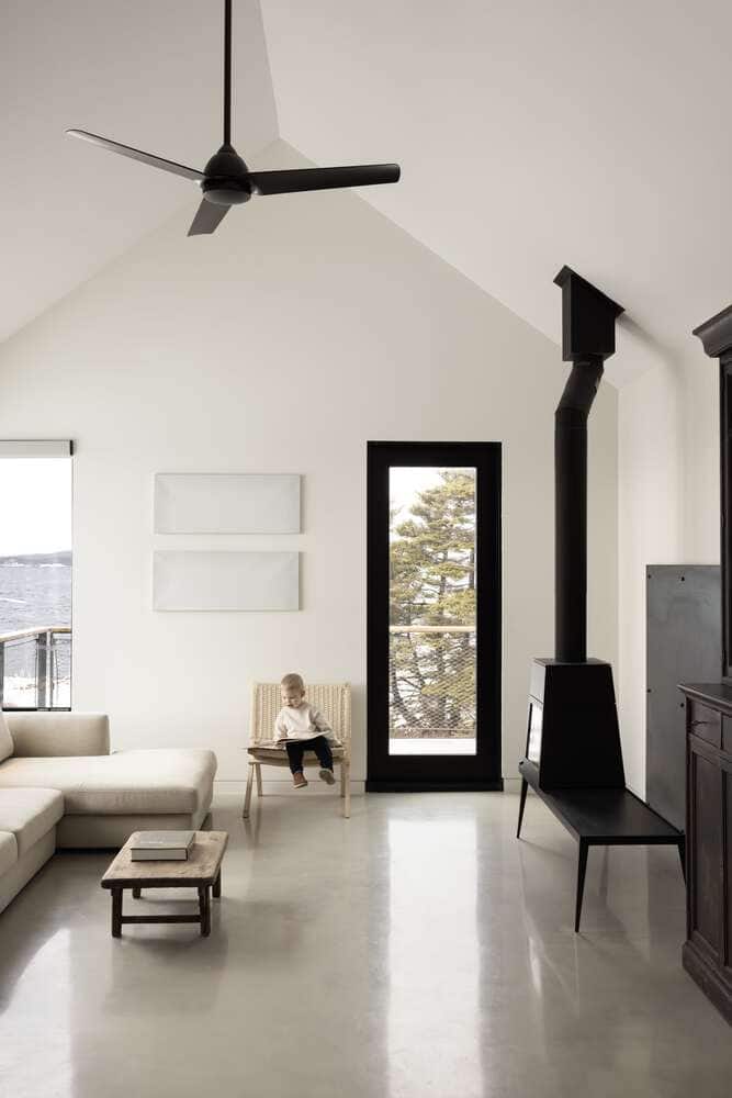 Living room scene at Tide Bound House by Peter Braithwaite Studio with a child seated near the wood stove and coastal views