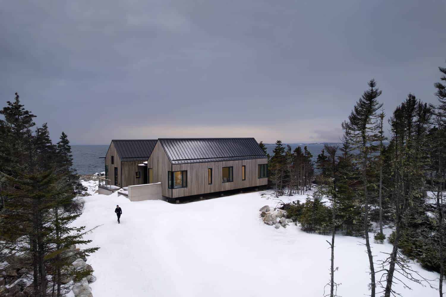 Tide Bound House by Peter Braithwaite Studio with a winter approach along the snowy driveway in Indian Harbour, Nova Scotia, Canada