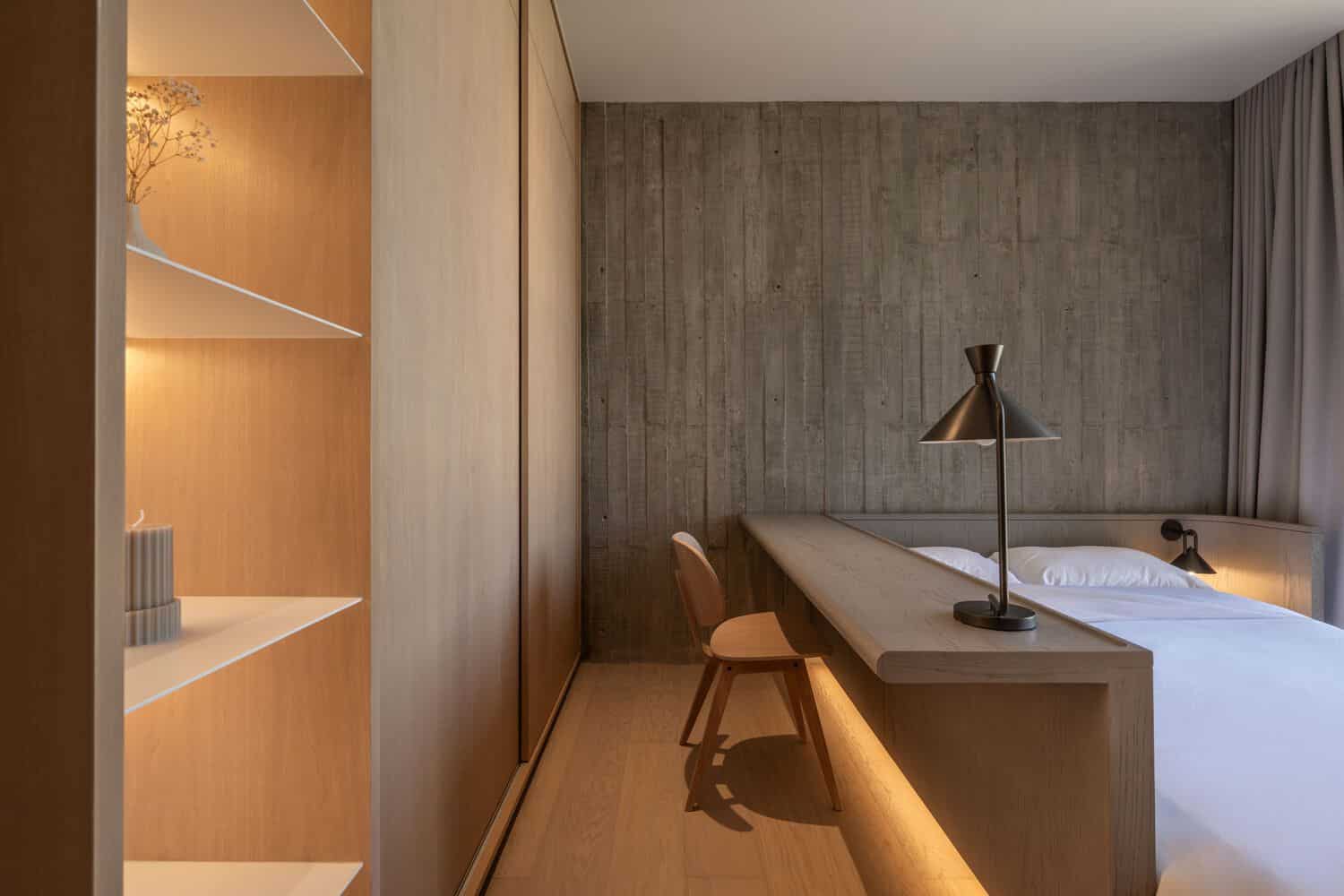 Minimal bedroom with desk and concrete feature wall at W House II by IDIN Architects in Thailand