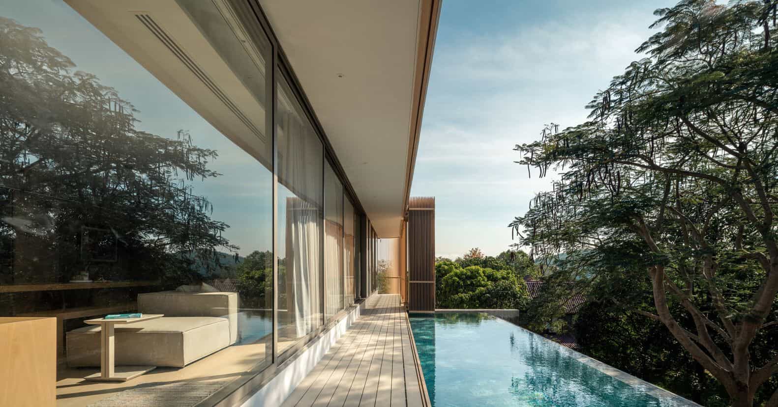 Modern luxury house with glass walls, infinity pool, and lush green trees, showcasing contemporary architecture and innovative design. Perfect for upscale living, blending indoor-outdoor spaces.