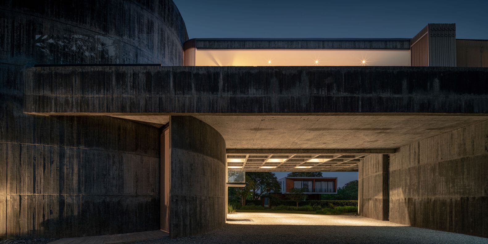 Night entrance framed by curved concrete wall at W House II by IDIN Architects in Thailand